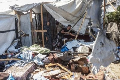Penduduk Gaza memeriksa keadaan khemah sementara di Khan Yunis yang separa musnah dibedil rejim Zionis.