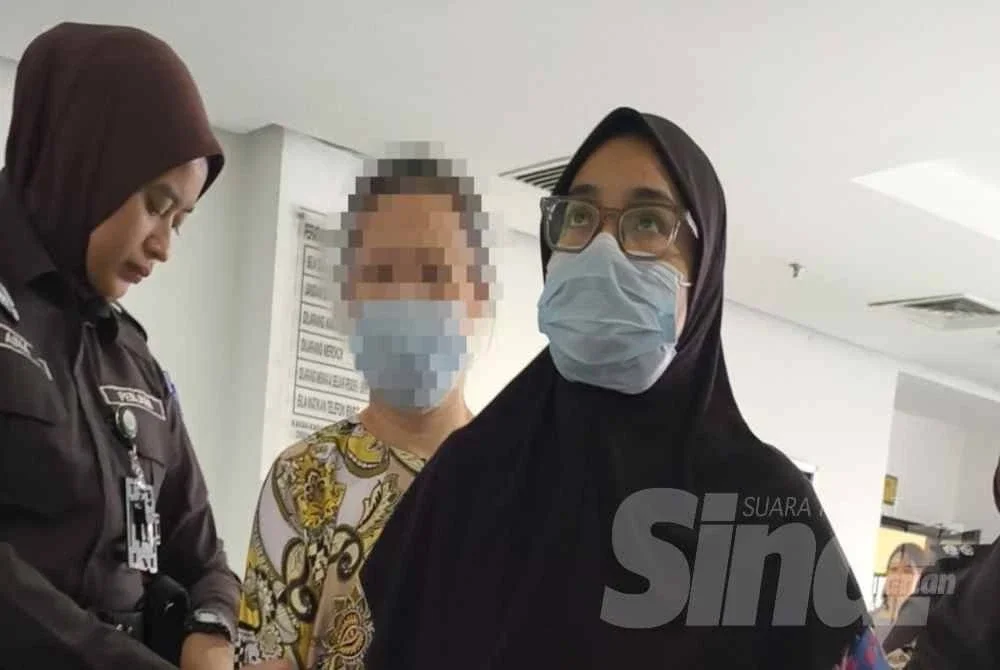 Ismanira (kanan) yang memakai baju kurung dan bertudung hitam dibawa ke Mahkamah Tinggi Shah Alam pada Rabu.