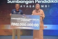Ahmad Azri (kiri) menyerahkan replika cek kepada Wan Nor Ashikin pada Majlis Aspirasi Pendidikan Yayasan MBI 2026 pada Rabu.
