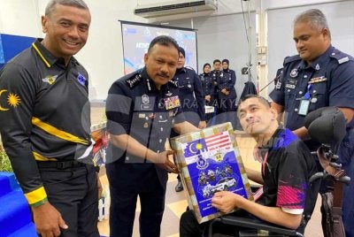 Mohd Yusoff (dua dari kiri) dan Alzafny (kiri) menyampaikan sumbangan pesakit kronik kepada kakitangan terpilih pada Sambutan Hari Polis ke 219 dan Program Flag Off sempena Bulan Kebangsaan dan Kibar Jalur Gemilang Tahun 2026 di IPK Kelantan di Kota Bharu pada Rabu. Foto: HAZELEN LIANA KAMARUDIN