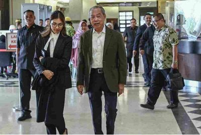 Muhyiddin (tengah) yang berdepan tujuh pertuduhan menyalahgunakan kedudukan serta pengubahan wang haram membabitkan projek Jana Wibawa hadir bagi perbicaraan kes itu di Mahkamah Tinggi, pada Rabu. Foto Bernama