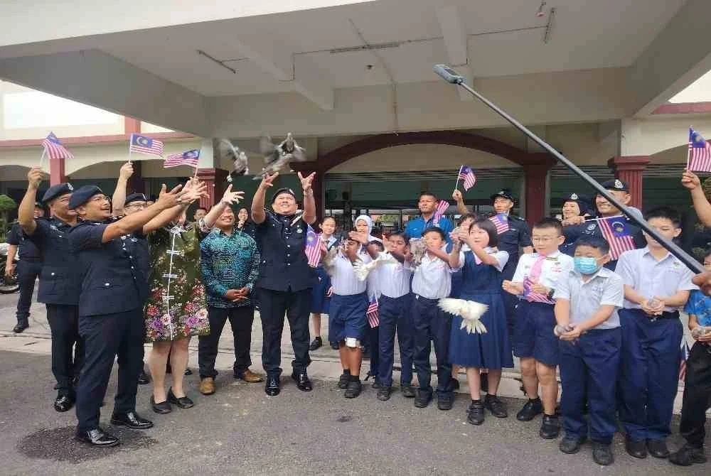 Norhizam (kiri) bersama murid SJKC Dengkil melepaskan burung merpati sebagai gimik Sambutan Bulan Kemerdekaan dan Kibar Jalur Gemilang 2026 Peringkat Ibu Pejabat Polis Daerah (IPD) Sepang pada Khamis.