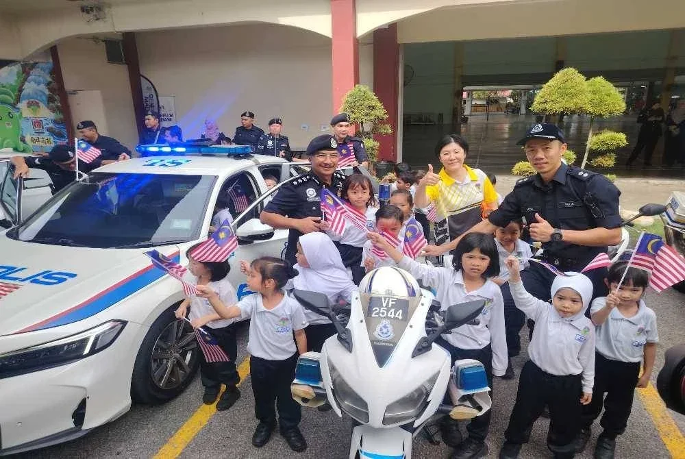 Norhizam (kiri) menyantuni murid SJKC Dengkil Sambutan Bulan Kemerdekaan dan Kibar Jalur Gemilang 2026 Peringkat Ibu Pejabat Polis Daerah (IPD) Sepang pada Khamis.