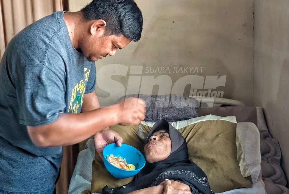 Muhammad Ashrol menyuap makanan kepada kakaknya Suriani yang terlantar sakit.