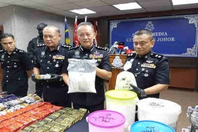  Hoo Chuan Huat ( tengah) menunjukkan dadah yang dirampas pada sidang akhbar IPK Johor pada Khamis.