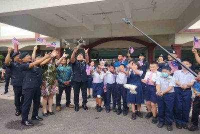 Norhizam (kiri) bersama murid SJKC Dengkil melepaskan burung merpati sebagai gimik Sambutan Bulan Kemerdekaan dan Kibar Jalur Gemilang 2026 Peringkat Ibu Pejabat Polis Daerah (IPD) Sepang pada Khamis.
