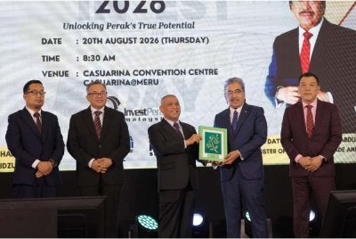 Saarani (tengah) menyampaikan cenderahati kepada Johari selepas hadir ke majlis Invest In Perak Day di Ipoh pada Khamis.