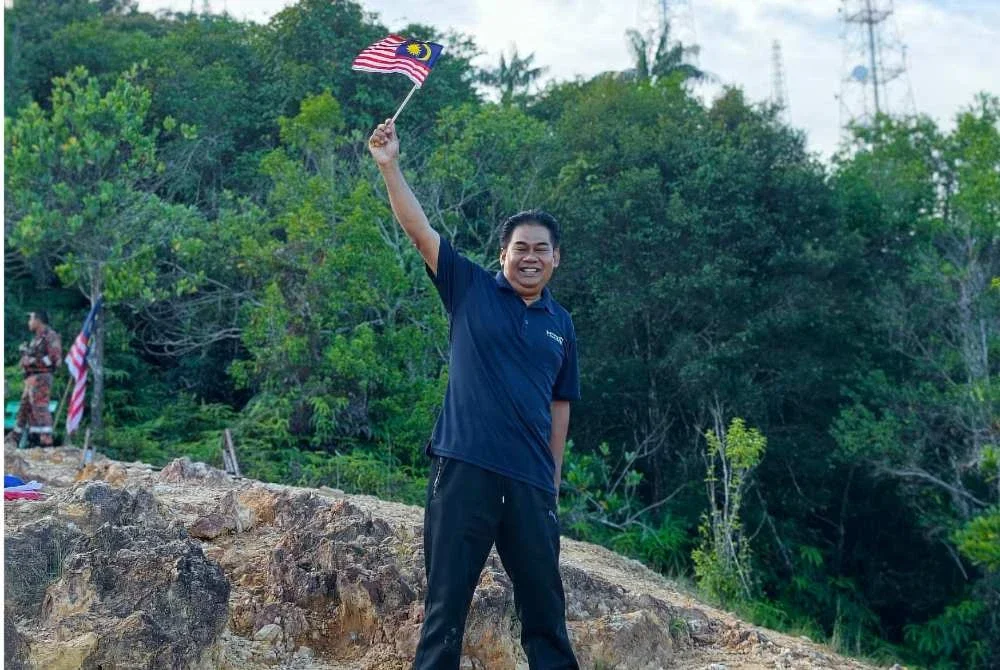 Zaid mengibarkan Jalur Gemilang sebaik tiba di puncak bukit sempena Program Pendakian Semarak Merdeka Anggota Beruniform Bersama Media 2026 ke Puncak Bukit Besar di Kuala Terengganu pada Khamis.