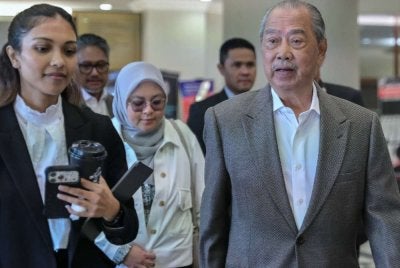 Muhyiddin (kanan) hadir di Mahkamah Tinggi pada Jumaat bagi perbicaraan tujuh pertuduhan menyalahgunakan kedudukan dan pengubahan wang haram. Foto: Bernama 