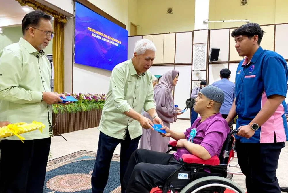 Tengku Mohamad Rizam (dua dari kiri) dan Mohd Anis (kiri) menyampaikan sumbangan zakat kepada penerima semasa Program Kesedaran Ibu Bapa Asnaf Terhadap Intervensif Awal Perkembangan Anak di Kompleks Islam Jubli Perak Sultan Ismail Petra di Kota Bharu pada Sabtu. Foto SINAR HARIAN/HAZELEN LIANA KAMARUDIN