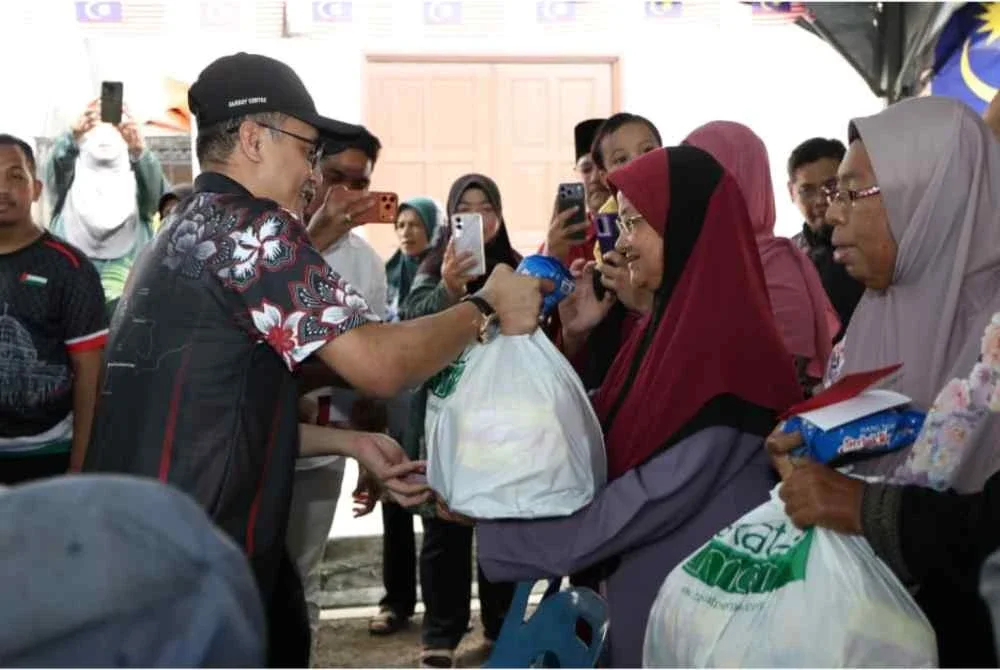 Mohamad (kiri) menyerahkan sumbangan kepada seorang asnaf sempena Kembara Konvoi Jejak Asnaf Peringkat Negeri Pulau Pinang 2026 di Balik Pulau pada Sabtu.