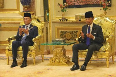 Anwar dan Sultan Hassanal Bolkiah mengaminkan doa selepas Istiadat Penganugerahan Darjah Kerabat Laila Utama Yang Amat Dihormati (D.K.) di Istana Nurul Iman. Foto Bernama