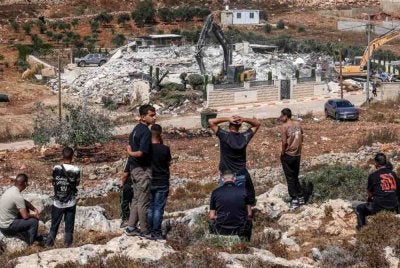 Lelaki Palestin menyaksikan jentolak Israel merobohkan sebuah bangunan milik Palestin atas alasan ketiadaan permit pembinaan di Qalandia, selatan Ramallah, Tebing Barat yang diduduki pada 17 Ogos 2026. Foto AFP