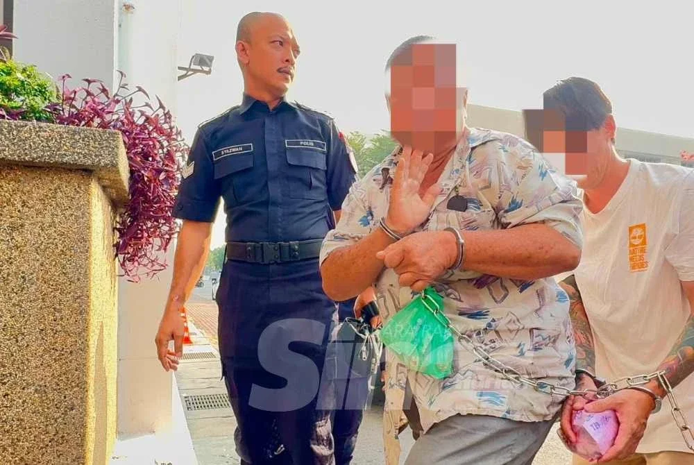 Suspek tiba di pekarangan mahkamah dalam keadaan tangan bergari sambil diiringi anggota polis.