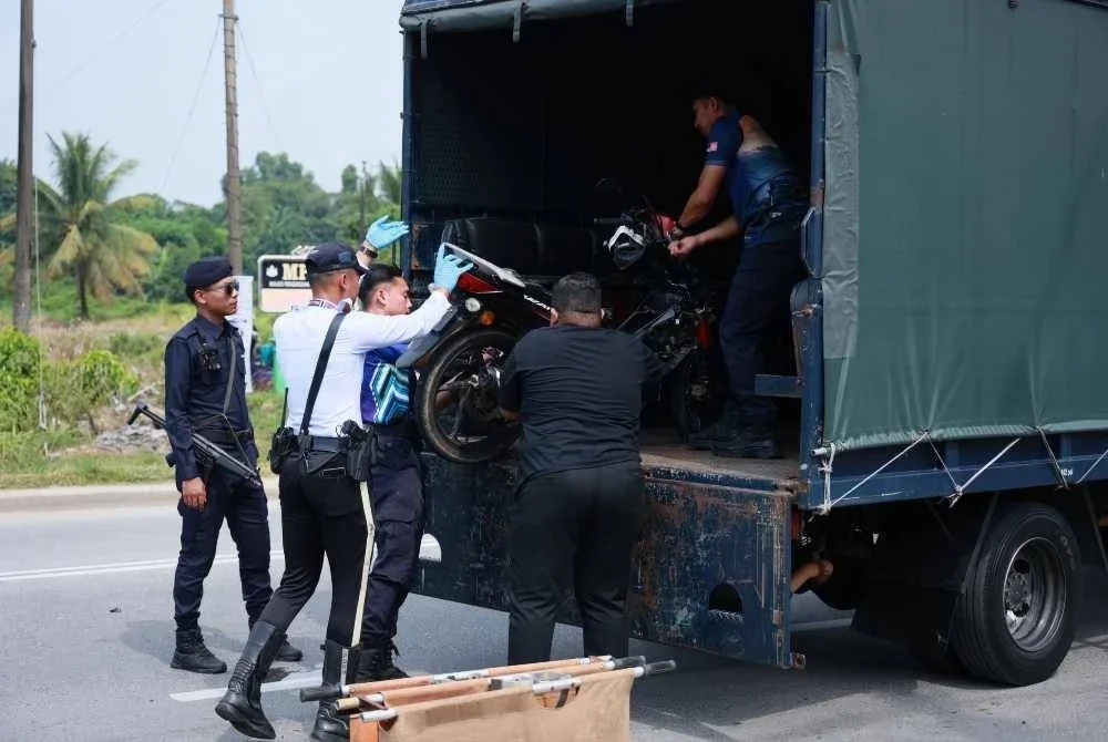 Anggota polis mengangkat motosikal mangsa yang terlibat dalam kemalangan di Kampung Paya Lada, Ketereh, Kota Bharu pada Isnin. FOTO: Tular