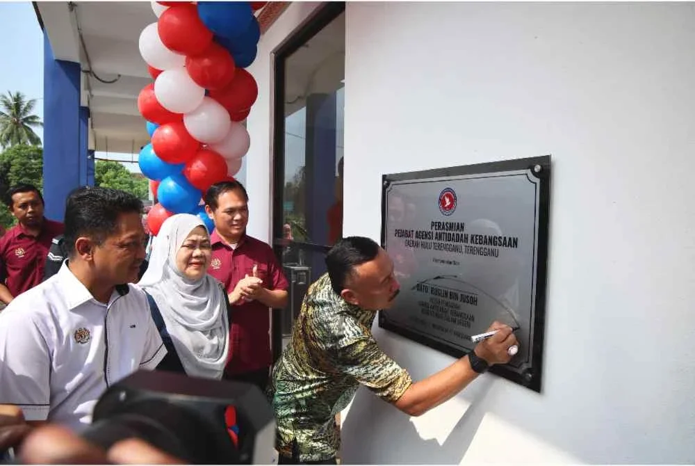 Ruslin (kanan) menandatangani plak perasmian Pejabat AADK Daerah Hulu Terengganu di Ajil pada Isnin.