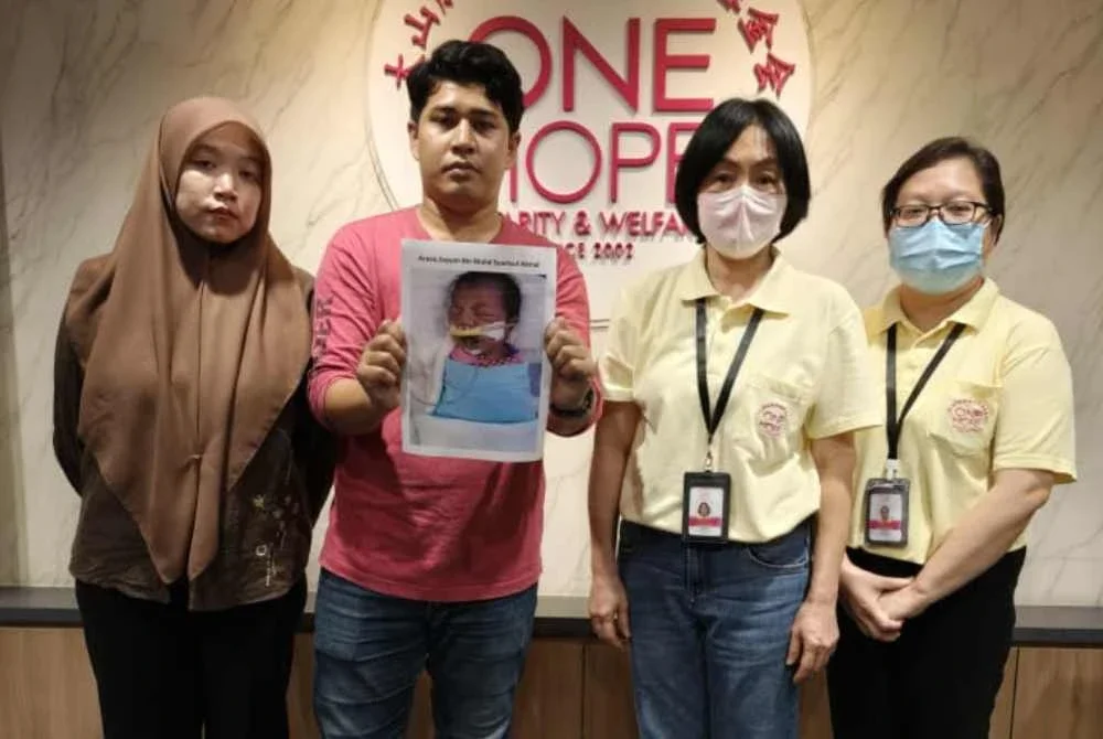 Muhamad Syamsul (dua dari kanan) bersama Masmira menunjukkan gambar anak mereka sambil diperhatikan oleh kakitangan One Hope Charity & Welfare.
