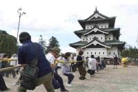 Orang ramai membantu menarik menara utama Istana Hirosaki menggunakan tali di wilayah Aomori, pada Ahad.