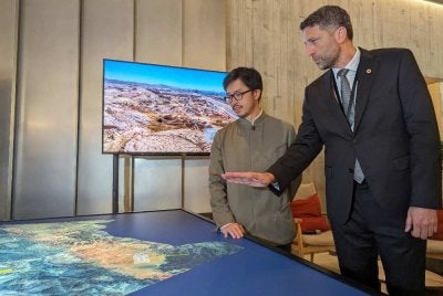 Pengarah Eksekutif NEOM, Tarek Qaddumi (kanan) menunjukkan peta projek NEOM kepada Nicholas Ho (kiri) pada pameran NEOM di Hong Kong, 19 April 2024. Foto AFP