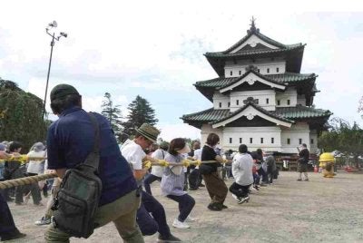 Orang ramai membantu menarik menara utama Istana Hirosaki menggunakan tali di wilayah Aomori, pada Ahad.