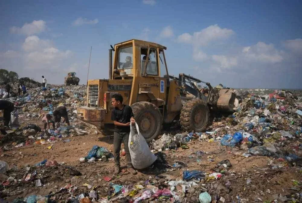 Seorang penduduk mengumpul sampah yang boleh digunakan untuk dibawa pulang.
