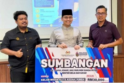 Mohammed Taufiq menyampaikan sumbangan replika cek RM30,000 kepada Presiden KMEK, M Hifzuddin Ikhsan (kanan).