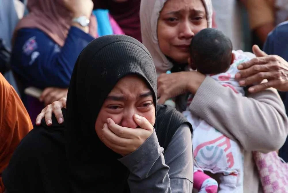 Nur Izzah tidak dapat menahan kesedihan selepas jenazah suami dan anak lelakinya ditemukan pasukan penyelamat selepas rumah keluarga mereka terbakar di Kampung Tok Jembal pada Rabu. Foto Bernama