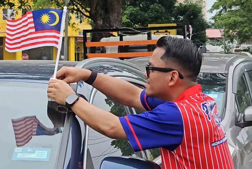 Mohd Affifi memasang Jalur Gemilang pada sebuah kenderaan di Pekan Meru, Kapar.