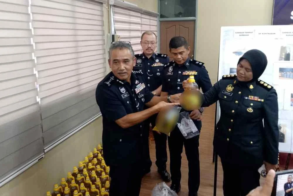 Adzli (kiri) menunjukkan minyak masak peket bersubsidi yang dibotolkan kepada minyak untuk tujuan keagamaan.