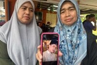 Rohana (kanan) dan Rosliza (kiri) menunjukkan gambar Muhamad Amin yang maut dalam kemalangan di Jalan Johor Bahru - Mersing pada Selasa