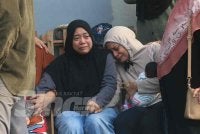 Nur Izzah (duduk, kiri) tidak mampu menahan sebak ketika ditemui di Jabatan Forensik Hospital Sultan Zainal Abidin (HoSZA) di Kuala Nerus pada Rabu.