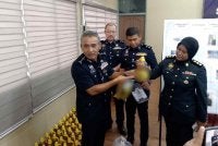 Adzli (kiri) menunjukkan minyak masak peket bersubsidi yang dibotolkan kepada minyak untuk tujuan keagamaan.