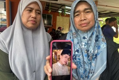 Rohana (kanan) dan Rosliza (kiri) menunjukkan gambar Muhamad Amin yang maut dalam kemalangan di Jalan Johor Bahru - Mersing pada Selasa