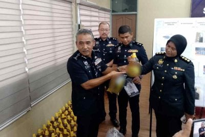 Adzli (kiri) menunjukkan minyak masak peket bersubsidi yang dibotolkan kepada minyak untuk tujuan keagamaan.
