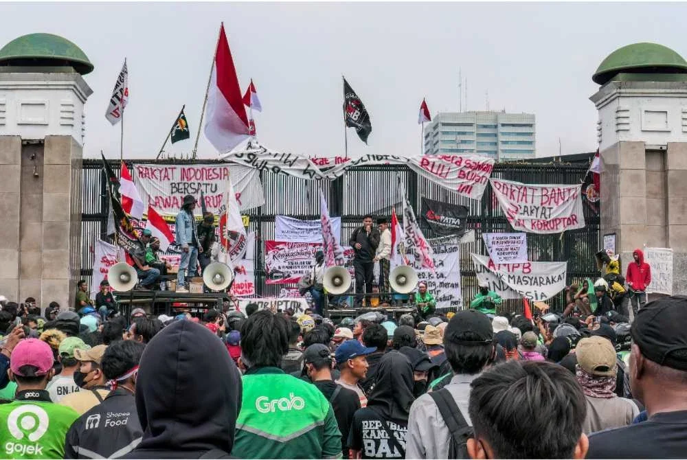 Penunjuk perasaan menyampaikan ucapan serta memasang poster dan sepanduk pada pintu pagar ketika demonstrasi di luar bangunan Parlimen di Jakarta. Foto: AFP