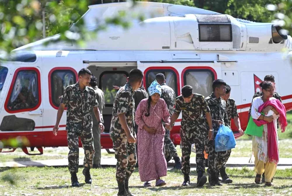 Anggota tentera mengiringi seorang wanita selepas diselamatkan dari lokasi banjir kilat di kem Trishuli, daerah Nuwakot, Nepal, pada 28 Ogos 2026. Foto AFP
