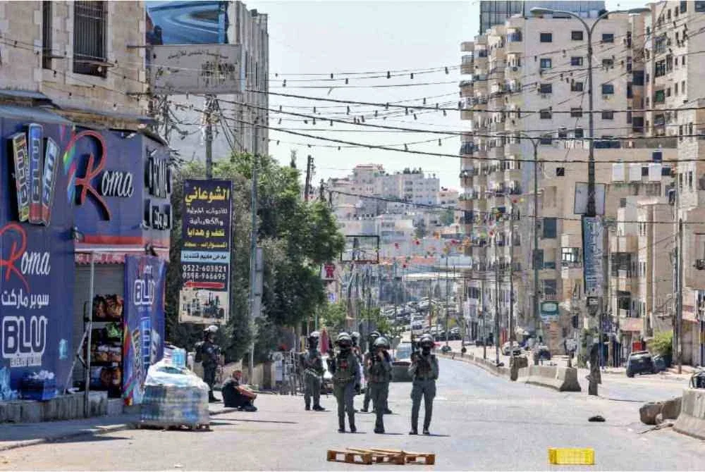 Anggota tentera Israel mengawal seorang lelaki Palestin yang ditahan ketika serbuan di Pusat Latihan Vokasional UNRWA, yang terletak antara kawasan kejiranan Kafr Aqab dan kem pelarian Qalandia, di selatan bandar Ramallah, Tebing Barat. Foto AFP