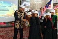 Pongot (kiri) menyerahkan cenderahati kepada pelajar-pelajar Sekolah Tahfiz Al-Habbah.