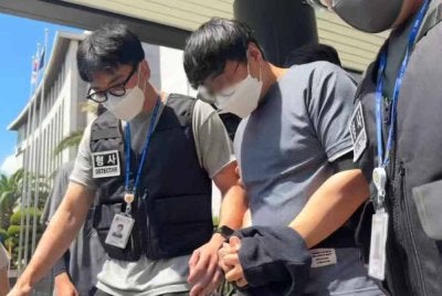 Pegawai polis (tengah) yang didakwa cuai mengendalikan 298 kes orang hilang dalam tempoh 17 bulan dibawa ke mahkamah pada Selasa. Foto Agensi