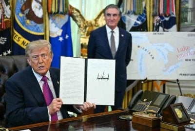 Trump bersama Setiausaha Dalam Negeri, Doug Burgum menunjukkan perintah eksekutif yang ditandatanganinya untuk menamakan semula Tasik Ontario sebagai Tasik Amerika di Pejabat Oval, Rumah Putih di Washington, DC, pada 27 Ogos 2026. Foto AFP