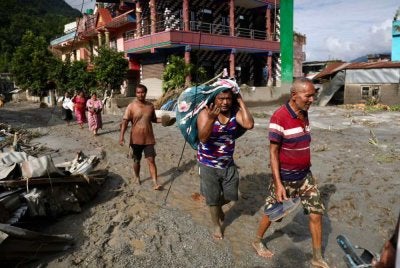 Penduduk tempatan berjalan melintasi rumah yang ditenggelami lumpur akibat banjir berhampiran Devighat, Perbandaran Bidur, di daerah Nuwakot, Nepal. Foto AFP