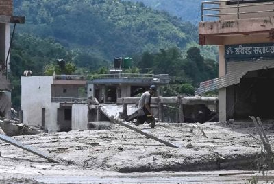 Seorang lelaki menyelamatkan barangan miliknya dari rumah yang ditenggelami lumpur selepas banjir kilat melanda kawasan Devighat di daerah Nuwakot, Nepal, pada 27 Ogos 2026. Foto AFP