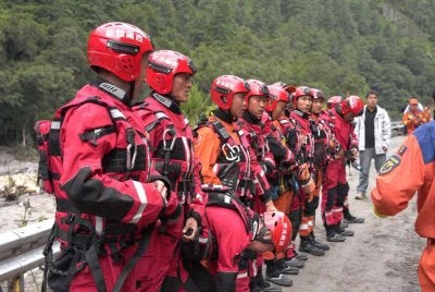Anggota pasukan bomba dan penyelamat berkumpul sebelum menjalankan operasi menyelamat di satu bahagian jalan menuju Pelabuhan Gyirong yang rosak akibat tanah runtuh dua hari lalu, di Daerah Gyirong, wilayah Tibet, China. - AFP