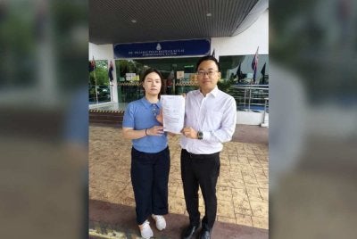 Bor Yang (kanan) menunjukkan laporan polis yang dibuat di IPD Kulai.