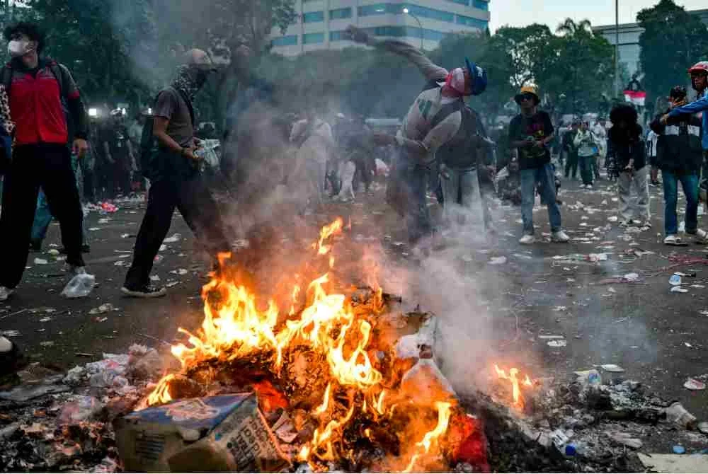 Penunjuk perasaan membaling objek berhampiran timbunan sepanduk yang terbakar. Foto: AFP