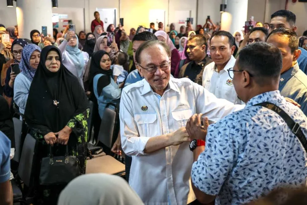 Anwar bersalaman dengan orang ramai ketika hadir pada Majlis Peluncuran Skim Usahawan Bangkit (SUB) Madani Permatang Pauh di Yayasan Aman pada Sabtu. Foto Bernama