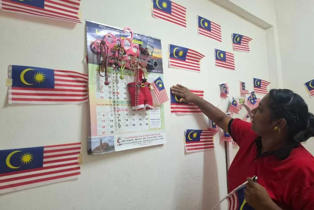 Anak Ratha, S Theinmooli, 42, menunjukkan Jalur Gemilang yang menghiasi dinding bilik tidur ibunya.