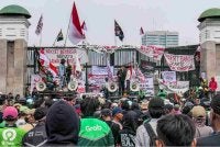 Penunjuk perasaan berucap dengan pelbagai sepanduk dipasang di pagar Parlimen Jakarta. Foto: AFP