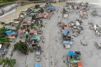 This aerial photograph shows houses covered heavily in sludge in the aftermath of flash floods at Devighat in Nepal's Nuwakot district on August 29, 2026. Nearly 3,000 people were still missing on August 29 and 633 confirmed dead after flash floods and landslides hit the Nepal-Tibet border. (Photo by Manan VATSYAYANA / AFP)