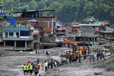 Para pekerja menggunakan jengkaut untuk membersihkan lumpur di Dhunge Bazaar, daerah Nuwakot, Nepal susulan kejadian banjir kilat dan tanah runtuh yang melanda kawasan sempadan Nepal-Tibet. Foto AFP
